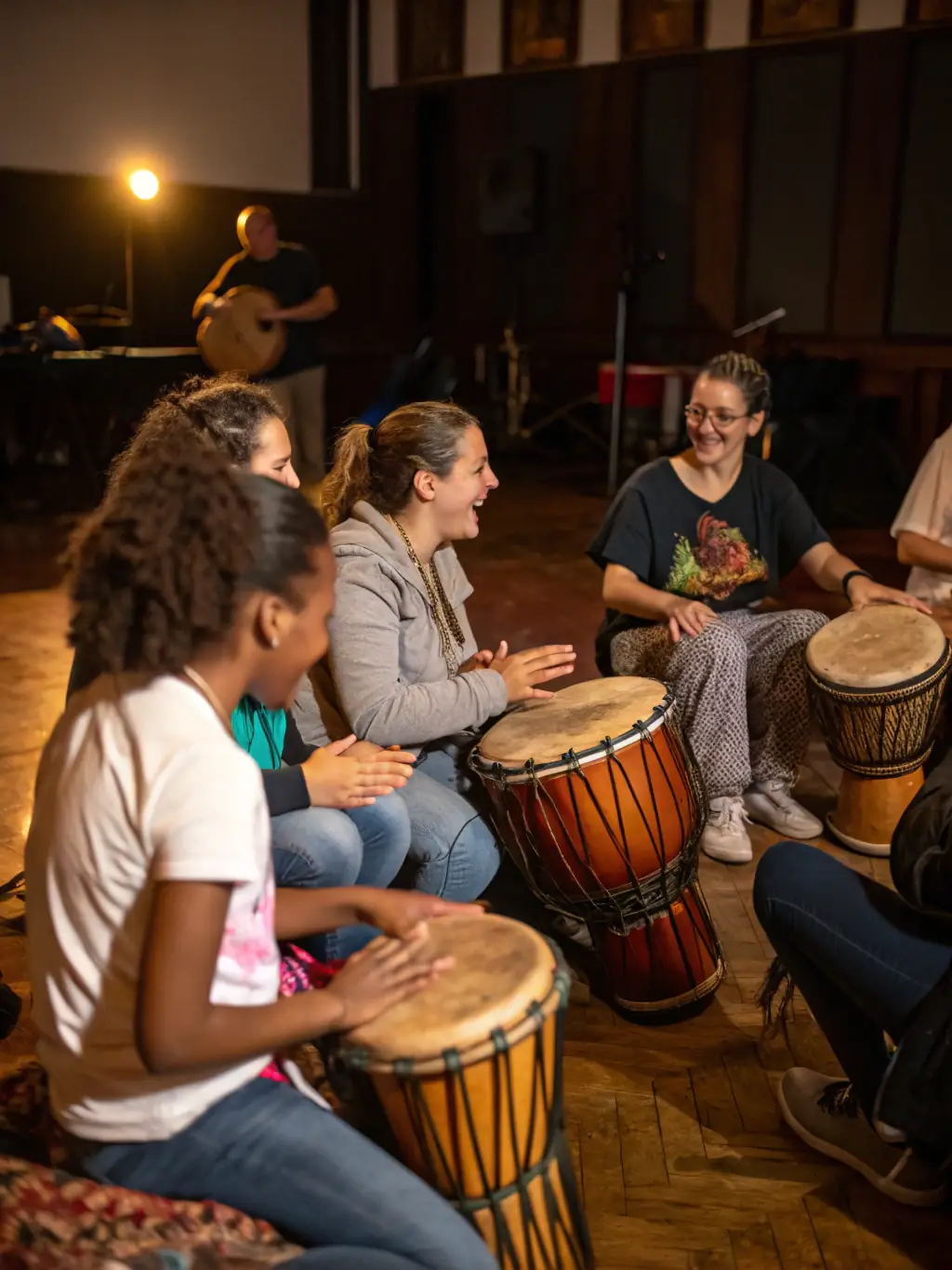 A vibrant photograph capturing a diverse group of community members participating in a drumming workshop at DE-SI-DE-LA-17's community music space, showcasing the energy and inclusivity of the program.